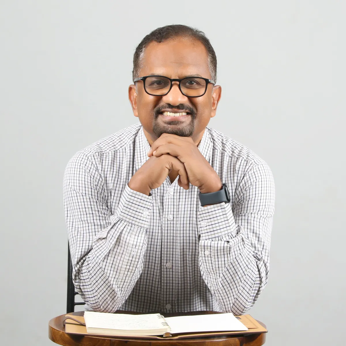 Sabu Thomas smiling, with an open notebook