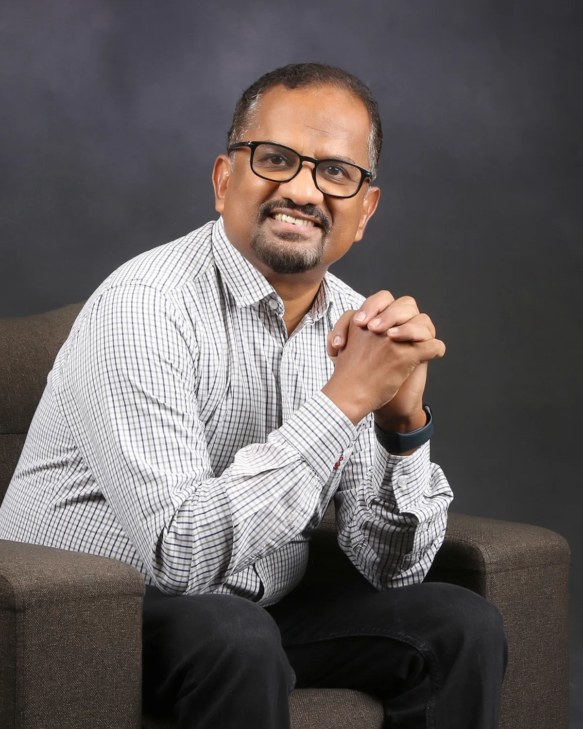 Sabu Thomas smiling, seated in an armchair